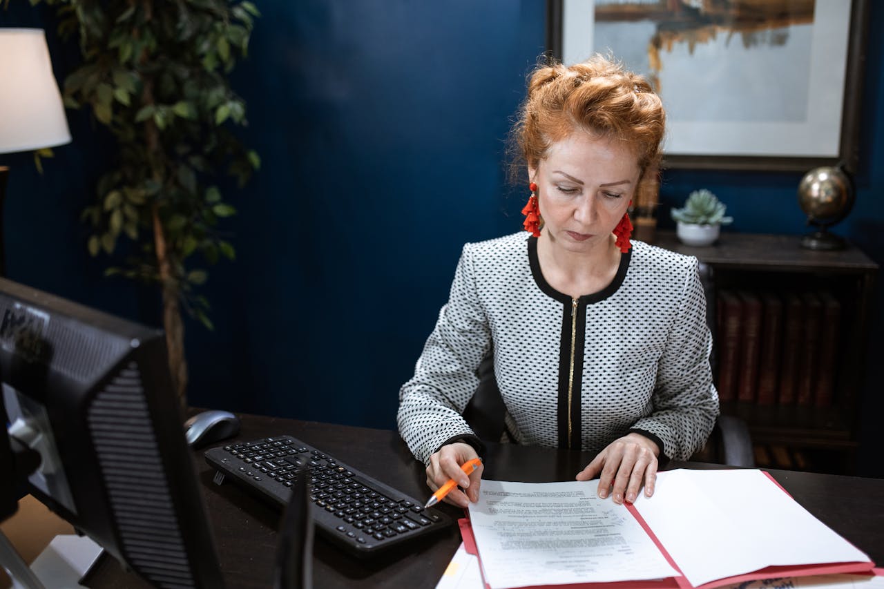 about-bg A focused woman working on paperwork in a modern office environment.