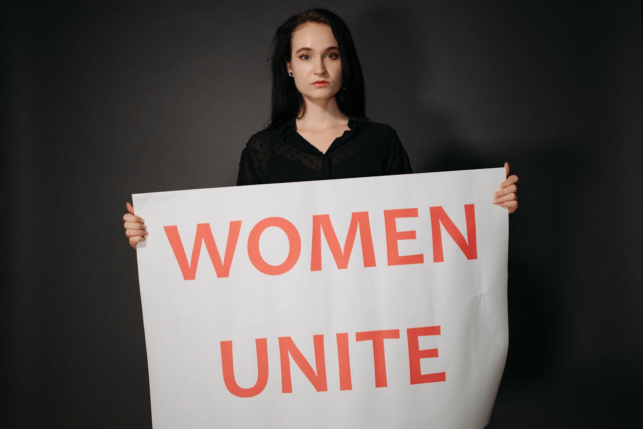 A woman holding a 'Women Unite' sign promoting feminism and equality.
